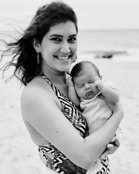 Portrait of smiling mother carrying son at beach