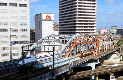 Train on railroad bridge against buildings on sunny day