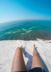 Low section of person in sea against sky