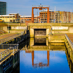 Reflection of buildings on river against sky