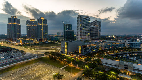 High angle view of city lit up against cloudy sky