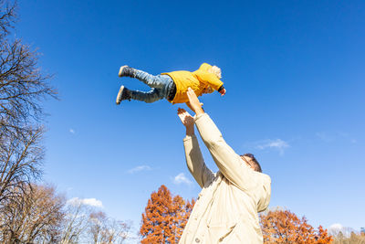 Low angle view of woman standing against clear blue sky