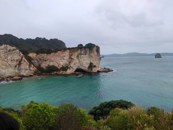 Scenic view of rocks by sea against sky