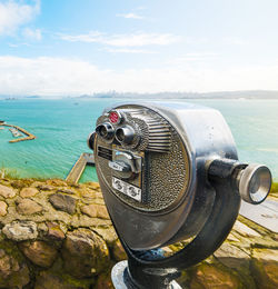 Close-up of coin-operated binoculars by sea against sky