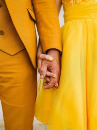 Midsection of couple holding yellow hands
