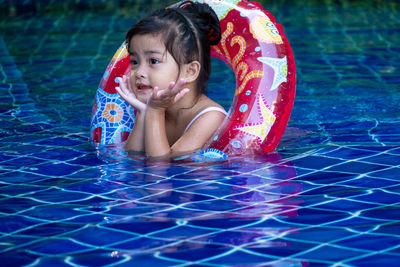 Cute girl with inflatable ring swimming in pool