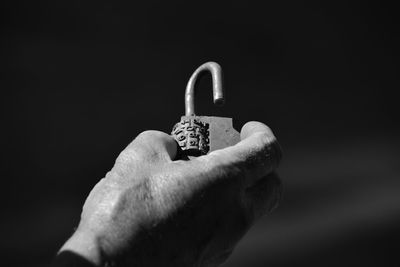 Close-up of hand holding padlock with numbers against sky