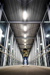 Rear view of woman walking in illuminated corridor