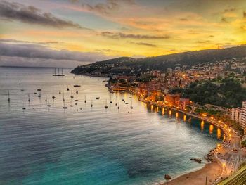 Panoramic view of sea and buildings against sky during sunset