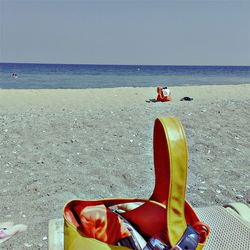 Man sitting on beach against clear sky