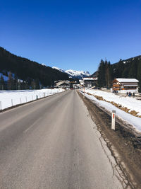 Snow covered road against clear blue sky