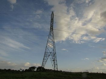 Low angle view of electricity pylon on field against sky