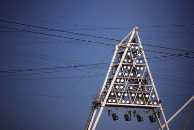 Low angle view of electricity pylon against blue sky