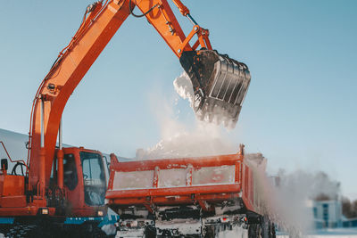 Snow removal after snowfall and blizzards. excavator loads snow into a truck.