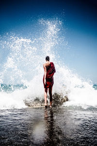 Full length of woman walking on shore at beach against sky