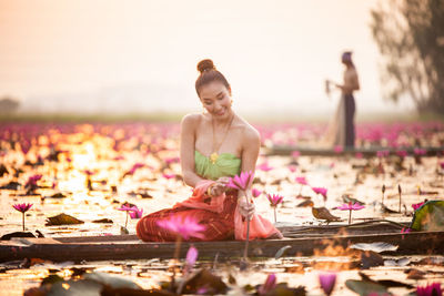 Woman holding lotus while sitting on boat in lake