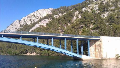 Bridge over river against clear blue sky