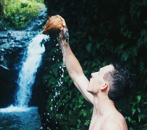 Woman splashing water in waterfall