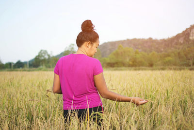 Rear view of woman standing in field against clear sky