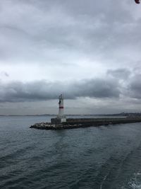 Lighthouse by sea against sky