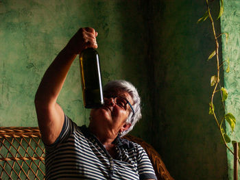 Drunk woman looking at wine bottle at home