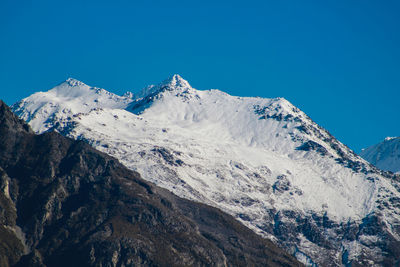 Scenic view of snowcapped mountains against clear blue sky