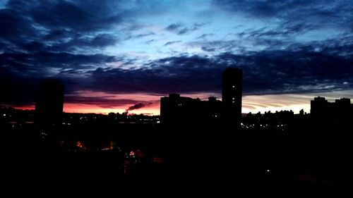 Silhouette factory against sky during sunset