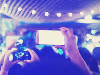 Cropped hand of woman holding mobile phone at concert