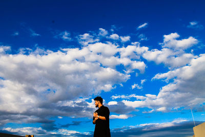 Side view of man standing against blue sky