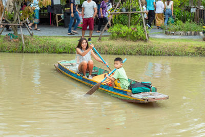 Portrait of mother with son sitting in boat on lake