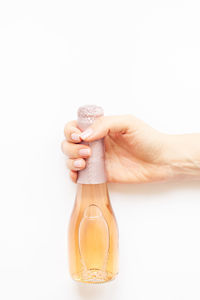 Close-up of hand holding glass over white background