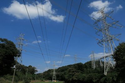 Low angle view of electricity pylon against cloudy sky