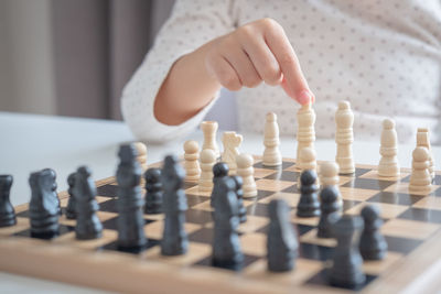 Midsection of girl playing chess on table