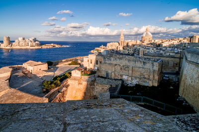 Buildings by sea against sky in city