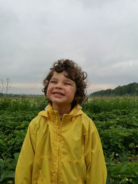 Portrait of boy standing on strawberry field with yellow rain jacket