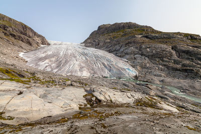 Scenic view of glacier and rocky mountains against clear sky