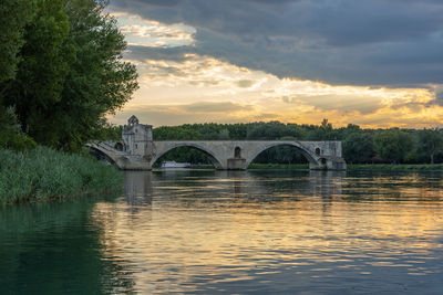 Arch bridge over river against sky during sunset