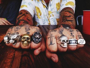 Midsection of hipster tattooed man wearing various finger rings