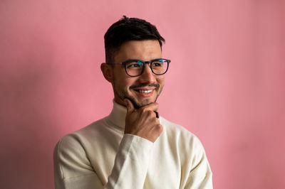 Portrait of young man wearing eyeglasses against wall