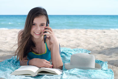 Young woman reading book on beach