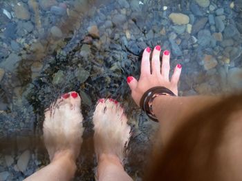 Low section of woman standing in river