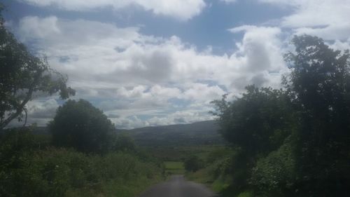 Road passing through landscape against cloudy sky