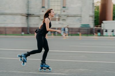 Full length side view of man skateboarding on city