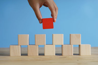 Close-up of hand toy on stack of wood against blue sky