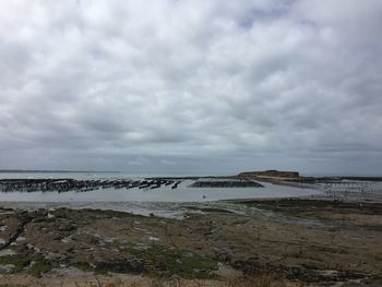 Scenic view of beach against cloudy sky