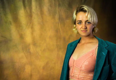 Portrait of young woman standing against yellow dress