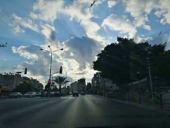 Cars on road against cloudy sky