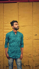 Young man looking away against wall