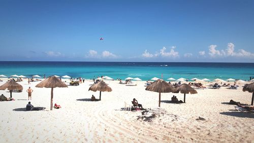 People at beach against sky during summer