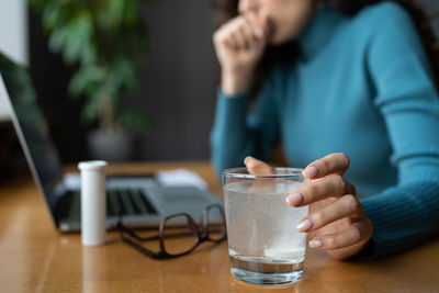 Closeup of painkiller dissolving in glass of water. sick business woman take medical pill in office